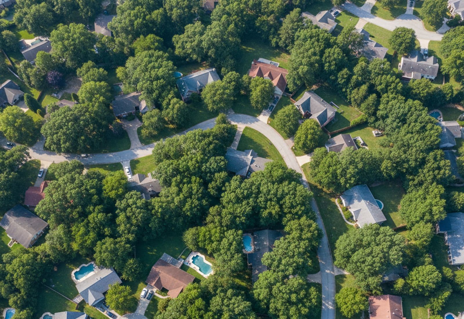 Aerial view of a suburban neighborhood with dense tree canopy